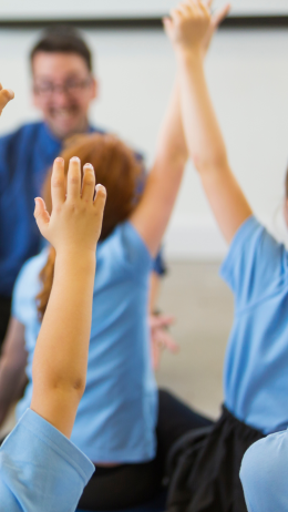 Students with hands up in a classroom