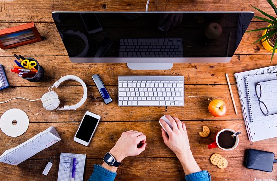 Birds eye view of a desk space with lots of technology scattered across it.