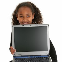 young child holding a laptop and smiling