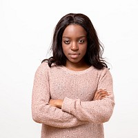 A college student with arms folded and a serious look.