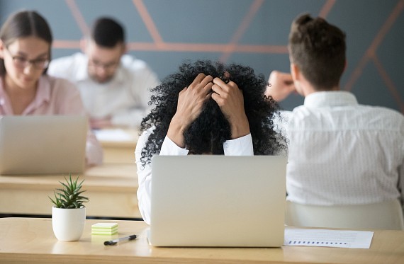 Woman in shared office space holds head in hands