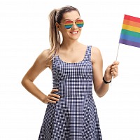 person with sunglasses on and a rainbow flag representing LGBTQIA+