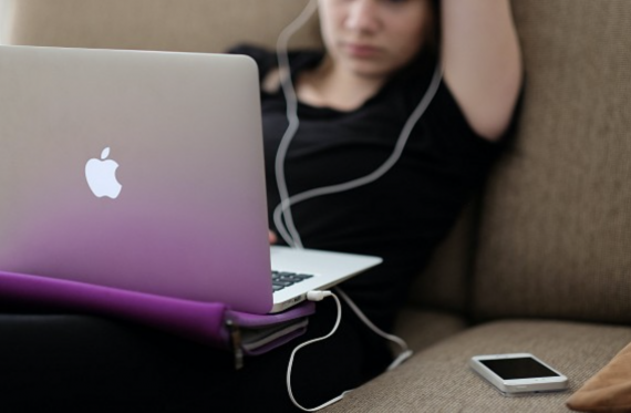 young person sat on laptop with headphones in