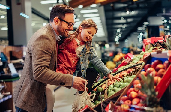 A parent and their child picking fruit at the supermarket