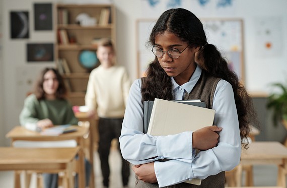 A student looks uncomfortable as men seem to say unkind things to her in the background.