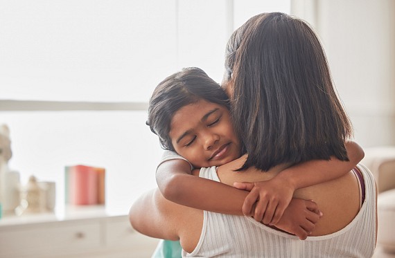 Young child hugs adult and looks content