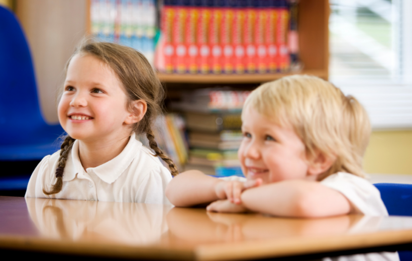 Children sat smiling and listening at school