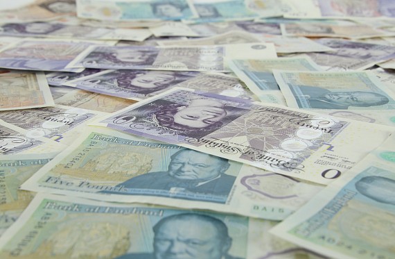 A selection of UK banknotes in a pile on a flat surface