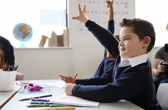 Boy with hand up in class