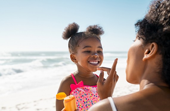 girl smiles as mum adds sun cream to her face