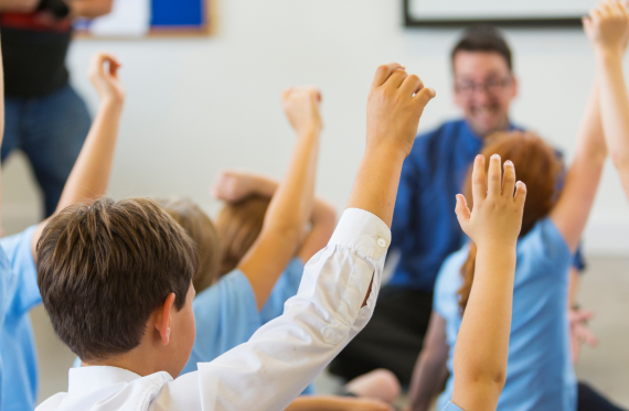 Children with raised hands in class