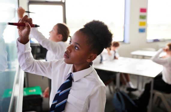 primary aged pupils raising their hands in class