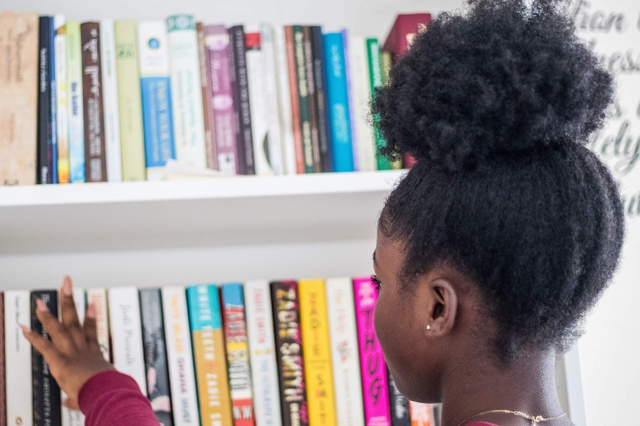 child looking at books on a bookshelf