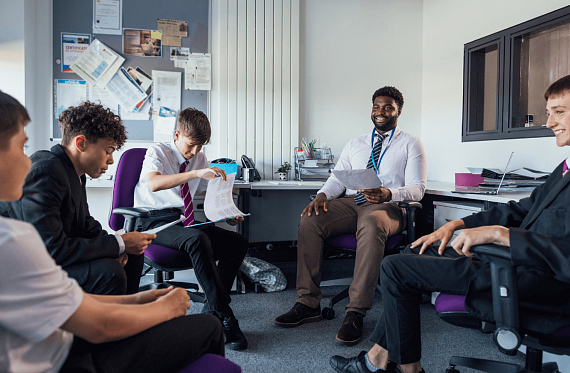 young people sat talking with their peers and teacher