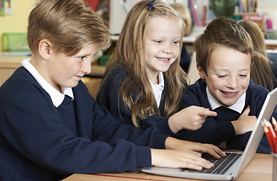 primary aged pupils working on a laptop