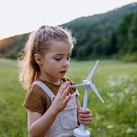 child holding small plastic wind turbine